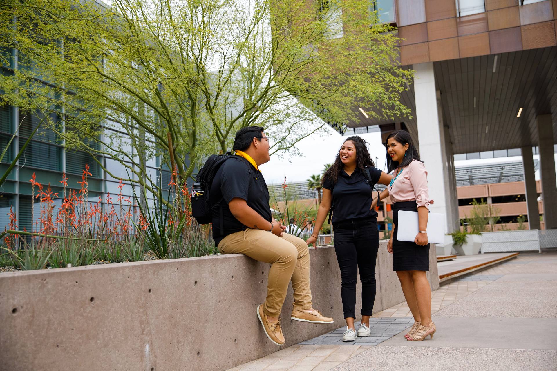 Two women talking to a seated man on the ASU campus