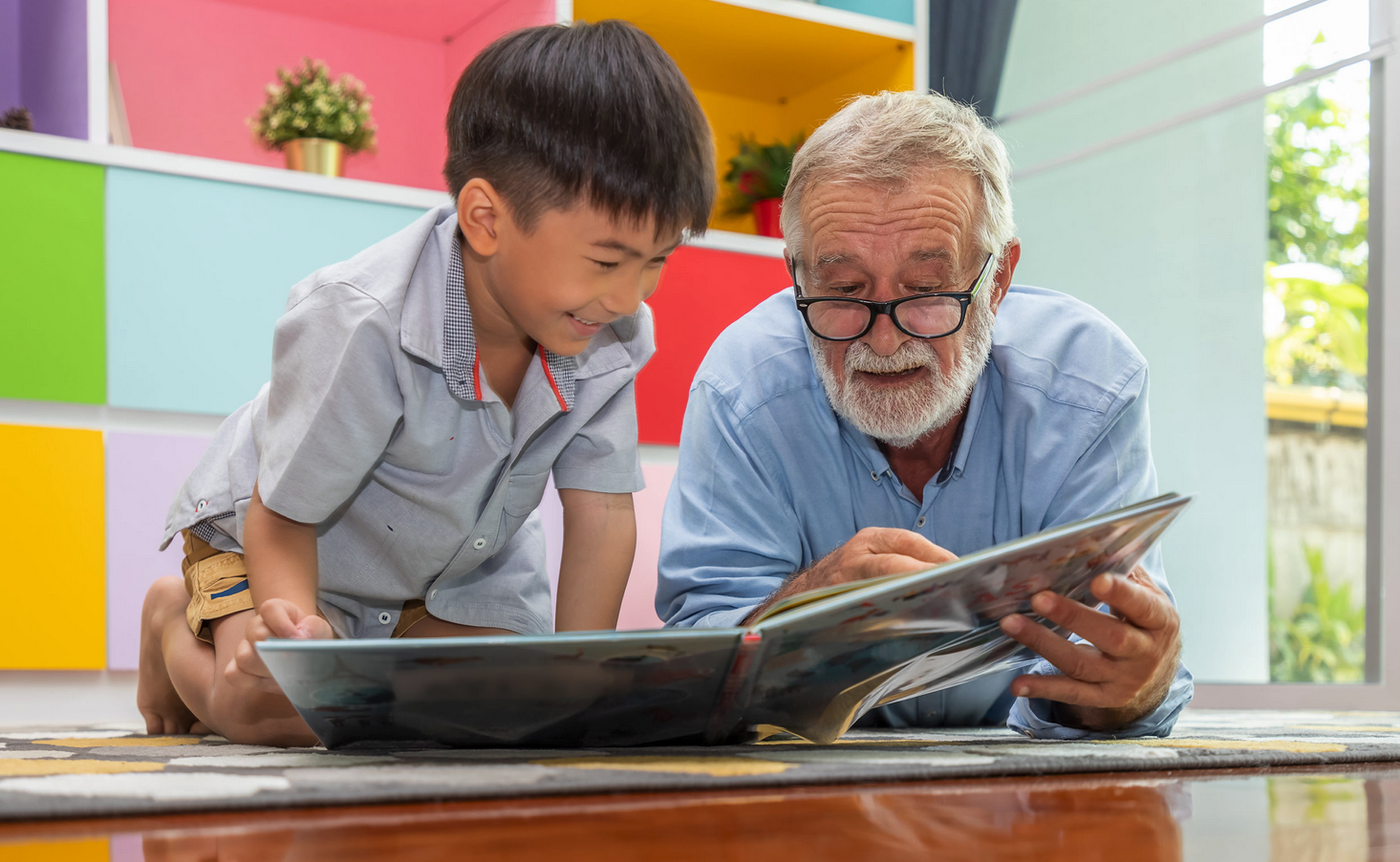 A senior citizen and child read a book together.