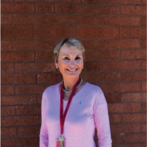 Judy Cummins' smiles while standing in front of a brick wall.