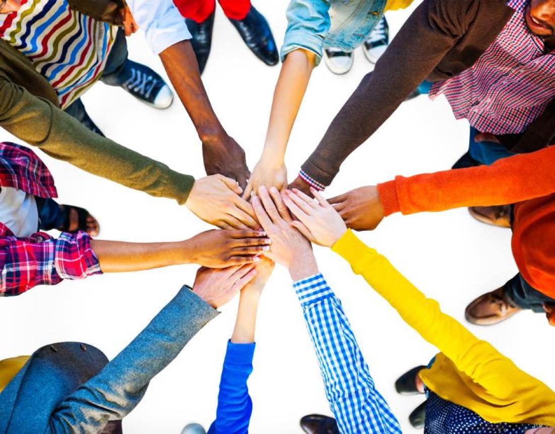 A group of people form a circle and each put one hand in the center.