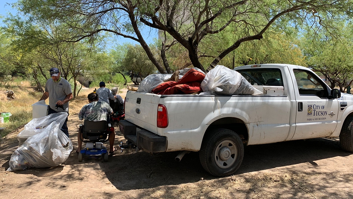 Volunteers pile the bags of trash into the back of a volunteer’s truck.