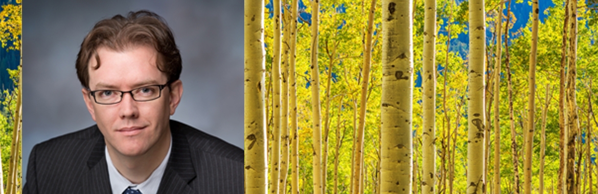 A professional photo portrait of Cothrun, Senior Director, Marketing & Development for the Sonoran Institute, sits next to an image of meadow of white aspen trees with yellow and green leaves.